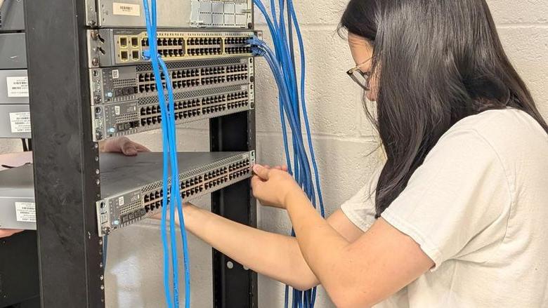 Penn State DuBois student Katy Fritz works on wiring and connecting one of the new Juniper switches that the campus received as part of the new partnership with Penn State IT.